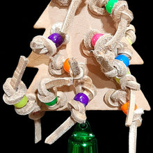 Load image into Gallery viewer, Bird toy made with a veggie tanned leather Christmas tree with double knotted leather lace and pony beads on both the front and back. Hangs on a short length of nickel plated chain with a vacuum coated bell on the bottom. Designed for small to intermediate sized birds (lovebirds, cockatiels, conures, quakers, etc).

