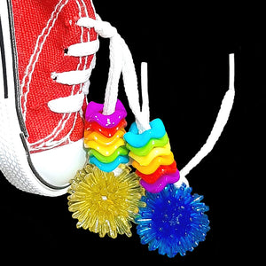 A miniature canvas sneaker decorated with brightly colored wiggle rings, mini spike balls and a charm. Makes a great foraging toy - simply hide a treat or two inside for foraging fun! Note: Sneaker does not have metal grommets like some do! Comes in assorted colors.  Hangs approx 6" including link.